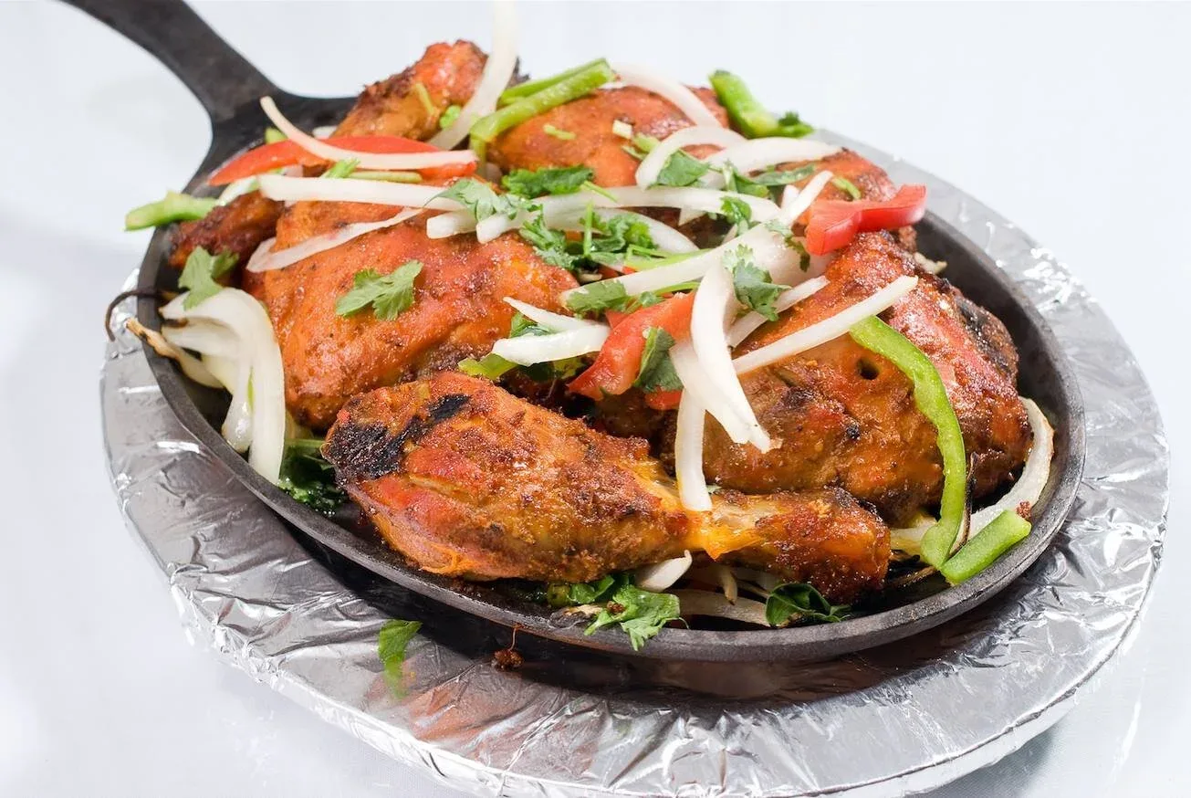 Tandoori chicken garnished with fresh coriander and sliced onion