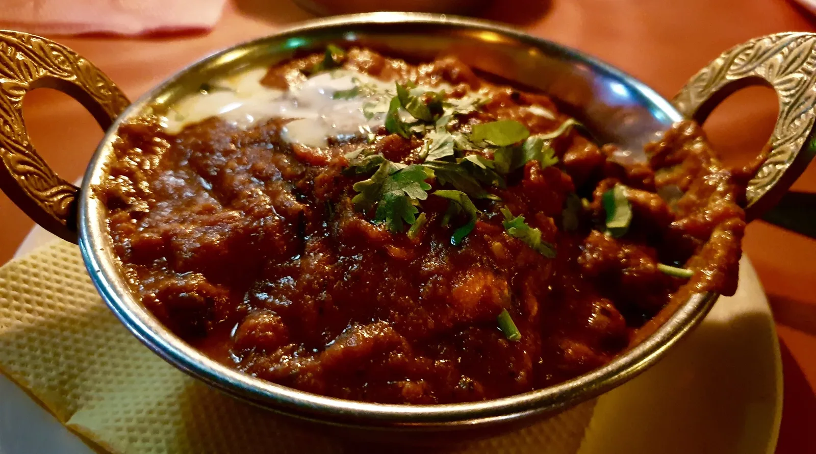Close-up of a curry in a serving dish garnished with coriander